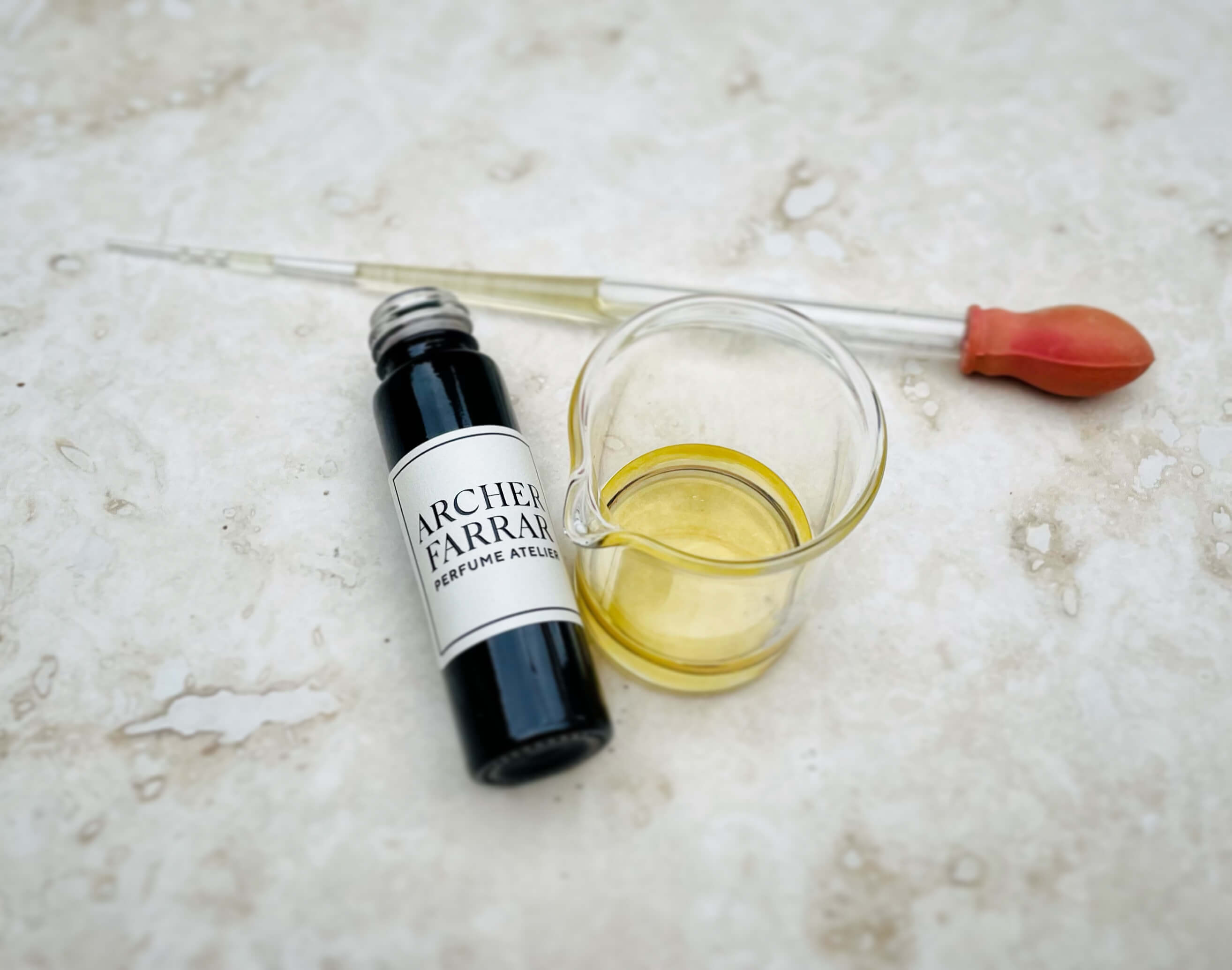 Archer Farrar natural perfume in beaker with pipette alongside 9ml roller bottle